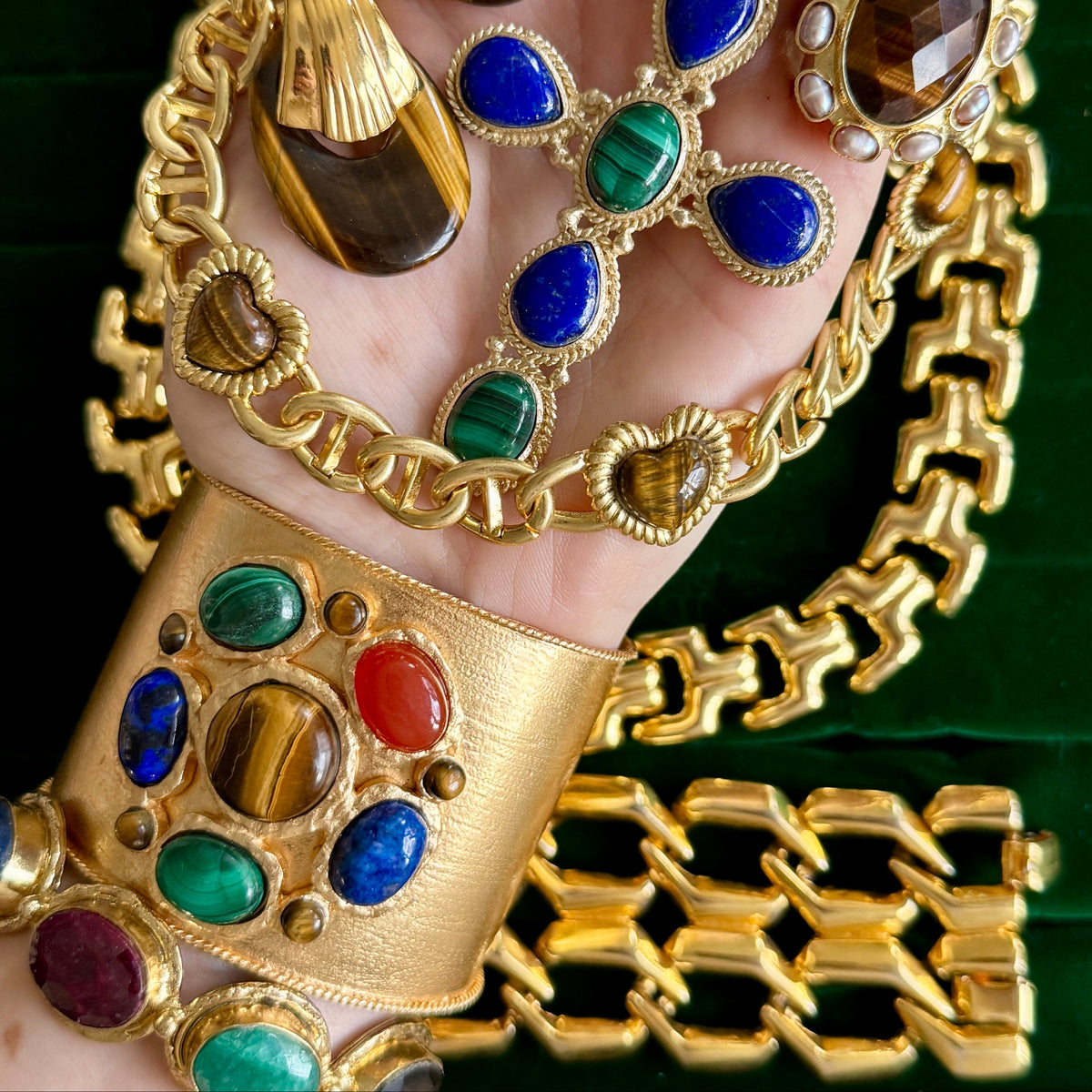 Styling shot with several gold pieces held together — chain necklaces, link bracelets and other stone-set cuffs; this listing is the tiger's eye and malachite cuff at the lower left.