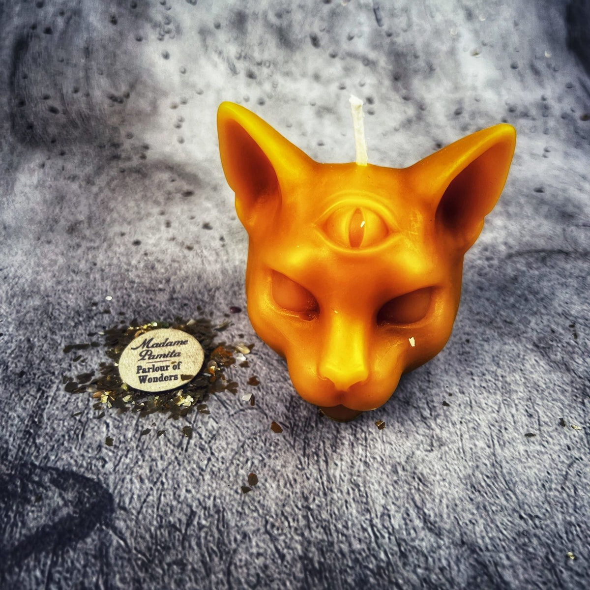 Bright orange cat head candle, the wick standing tall between the ears.