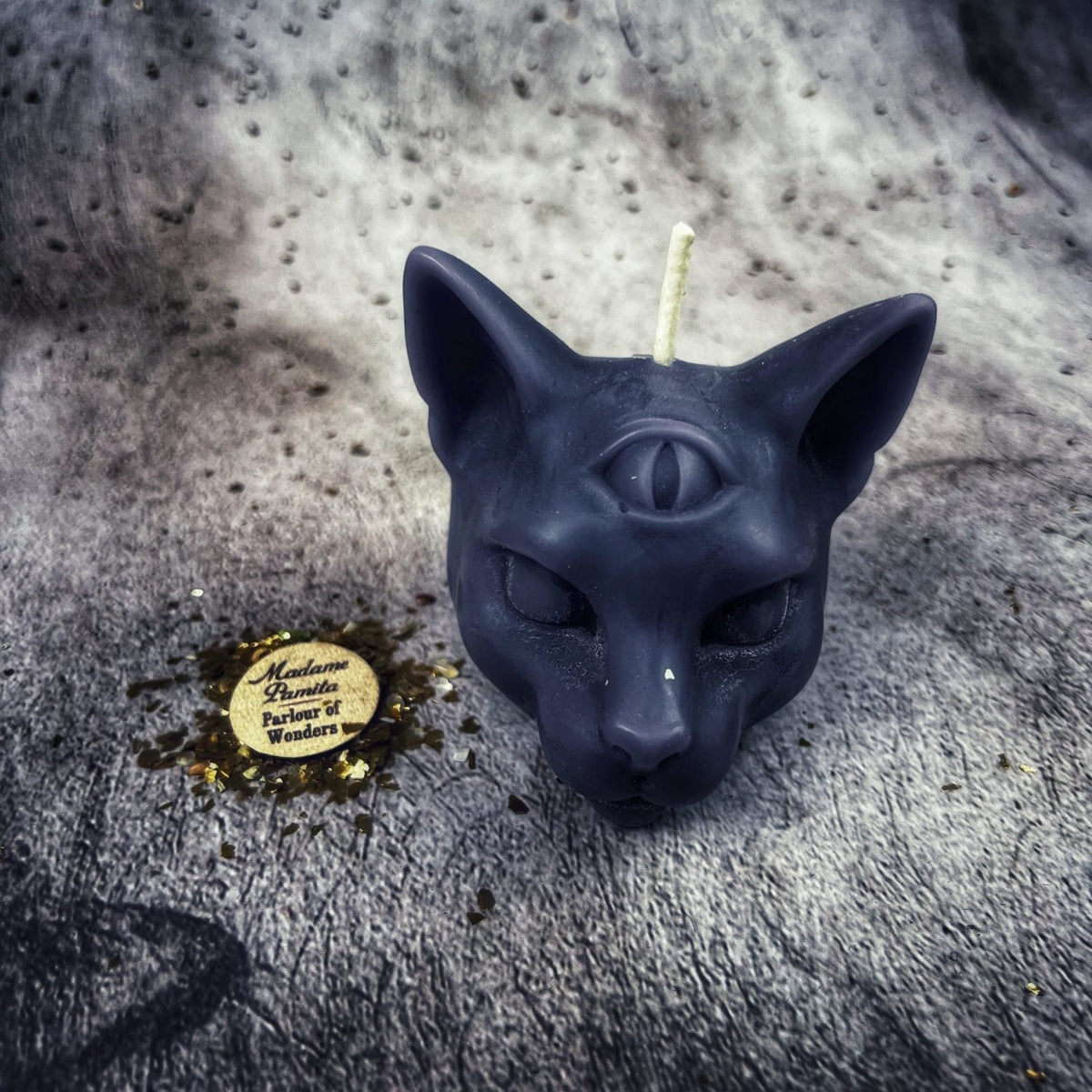 Navy-black cat head candle, the relief readable only through highlights.