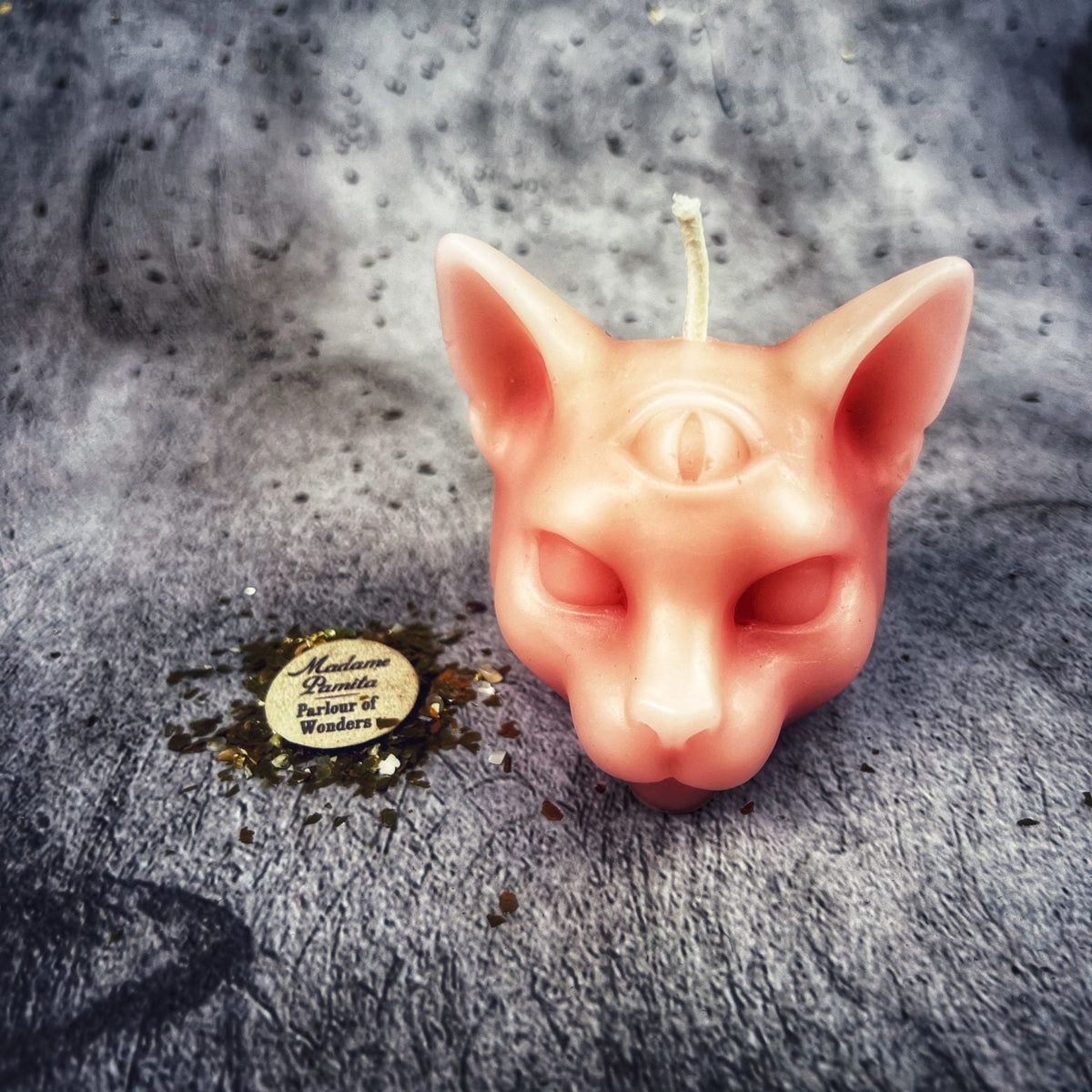 Salmon-pink cat head candle, the third eye and half-closed eyes clearly molded.