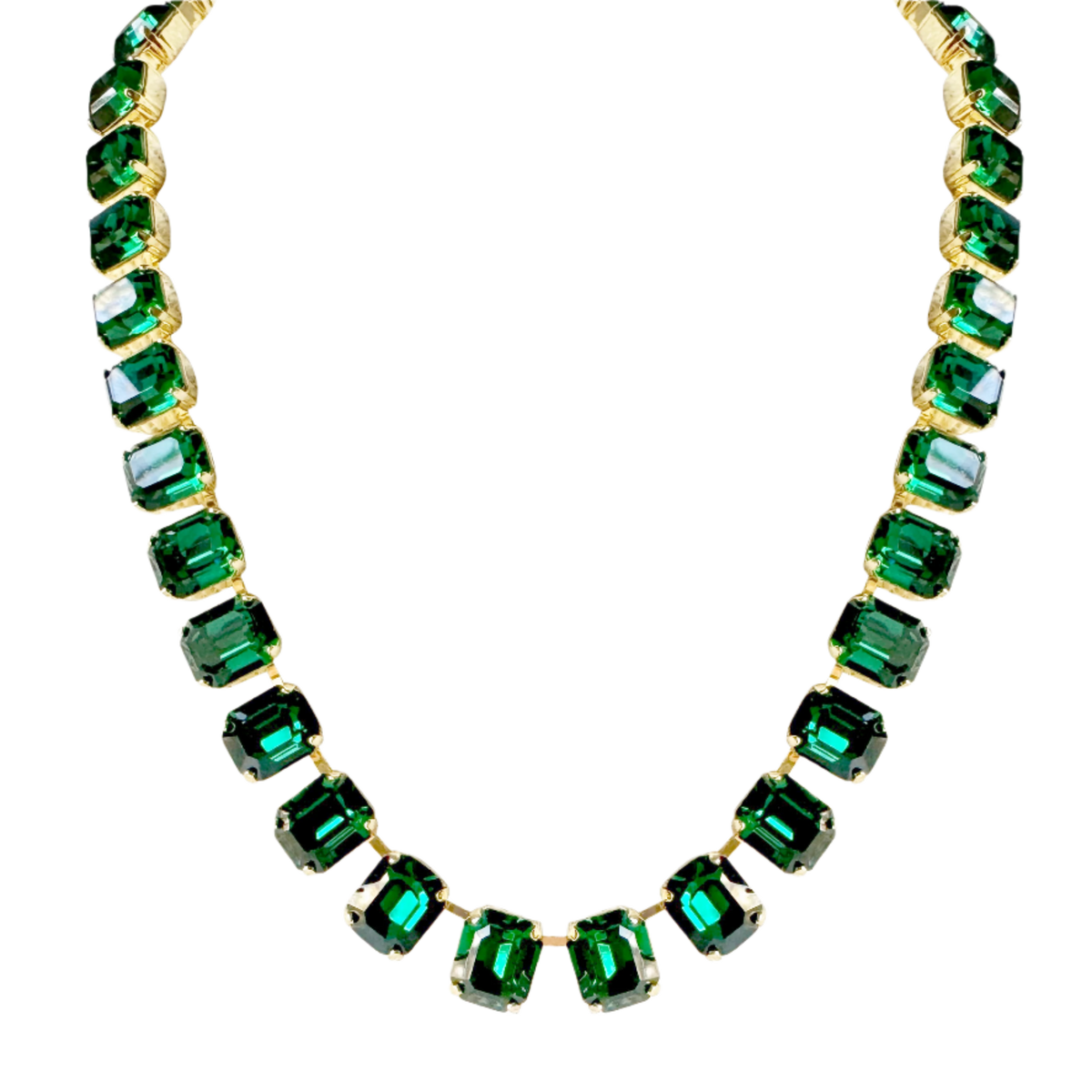 Close-up of the green crystal necklace on black, the emerald-cut stones held in gold-tone claw settings.