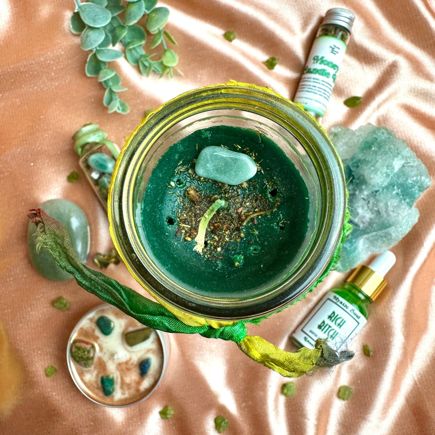 Close-up of the Money Drawing candle showing the dressed herbs and green aventurine on the wax.