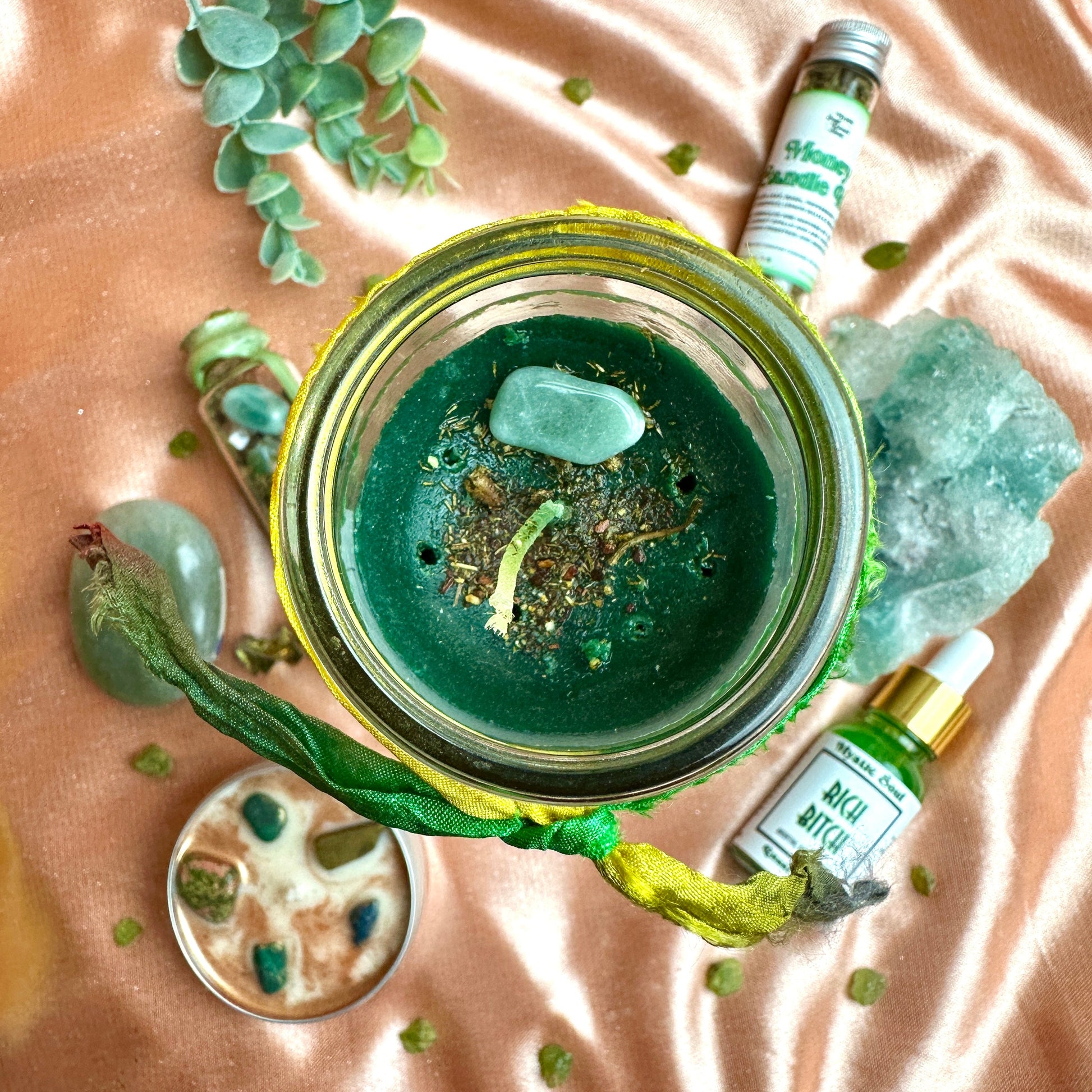 Close-up of the Money Drawing candle showing the dressed herbs and green aventurine on the wax.