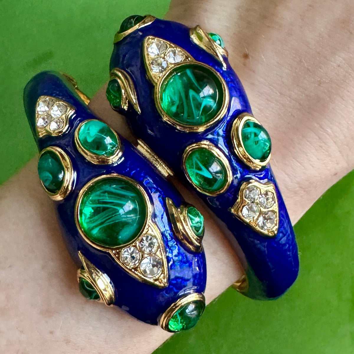 The cobalt blue snake cuff worn on a wrist, the two heads meeting across the top of the wrist.