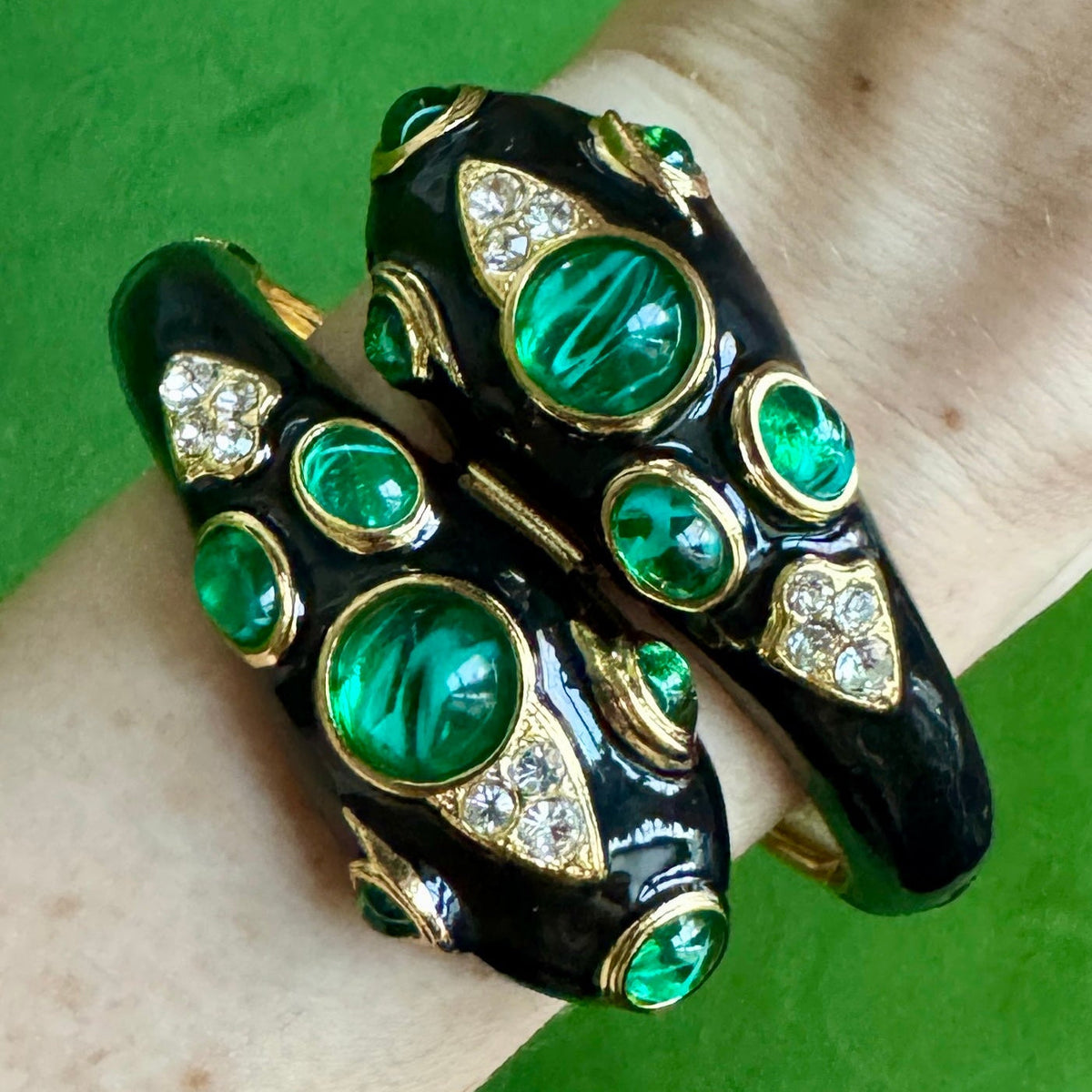 The black snake cuff worn on a wrist, the two enamelled heads meeting across the top of the wrist.