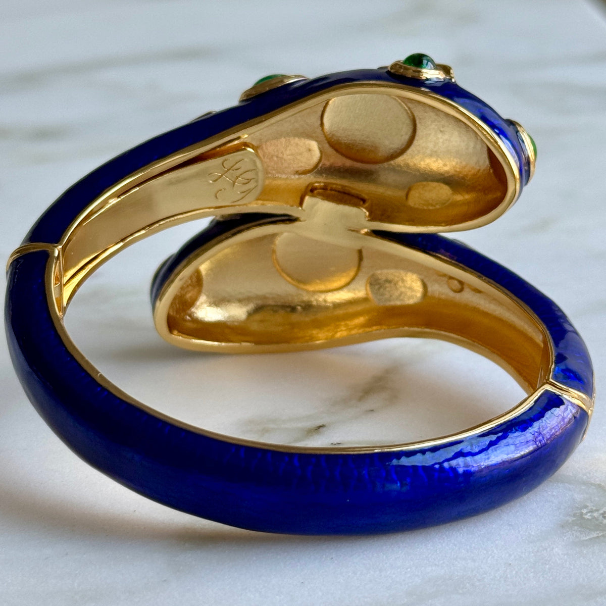 Inside view of the cobalt blue cuff on marble, showing the gold interior, the hinge and an engraved maker's mark.