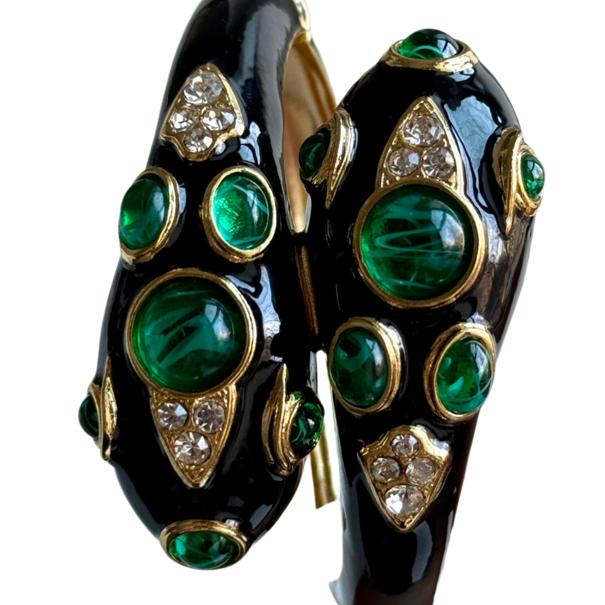 Close-up of the two snake heads in glossy black enamel, with large swirled green cabochons, smaller green ovals and shield-shaped clear pavé panels.