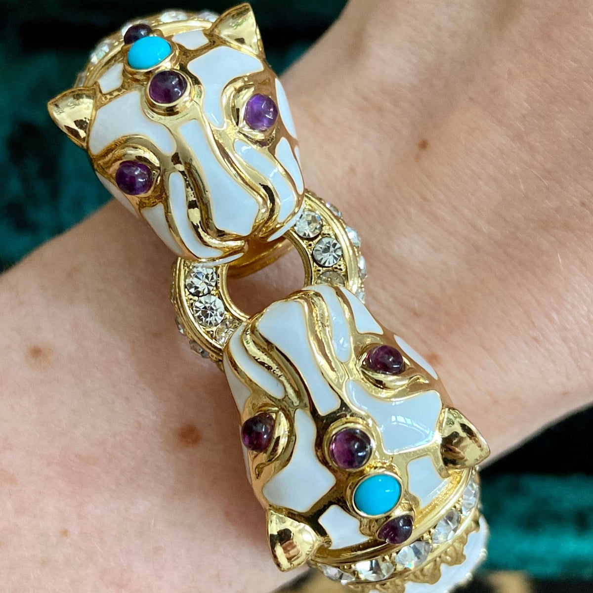 Close-up of the two panther heads in white enamel with purple and turquoise-blue cabochons and pavé-set clear collars.