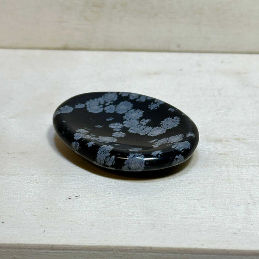 Smooth oval snowflake obsidian comfort stone with white cristobalite patterns on black volcanic glass