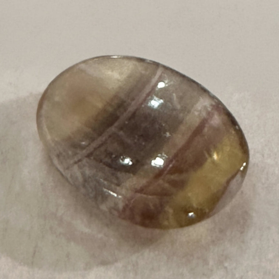 A polished fluorite comfort stone with translucent green and purple banding.