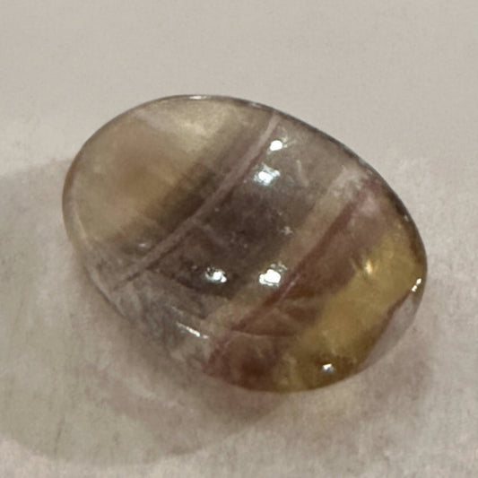 A polished fluorite comfort stone with translucent green and purple banding.