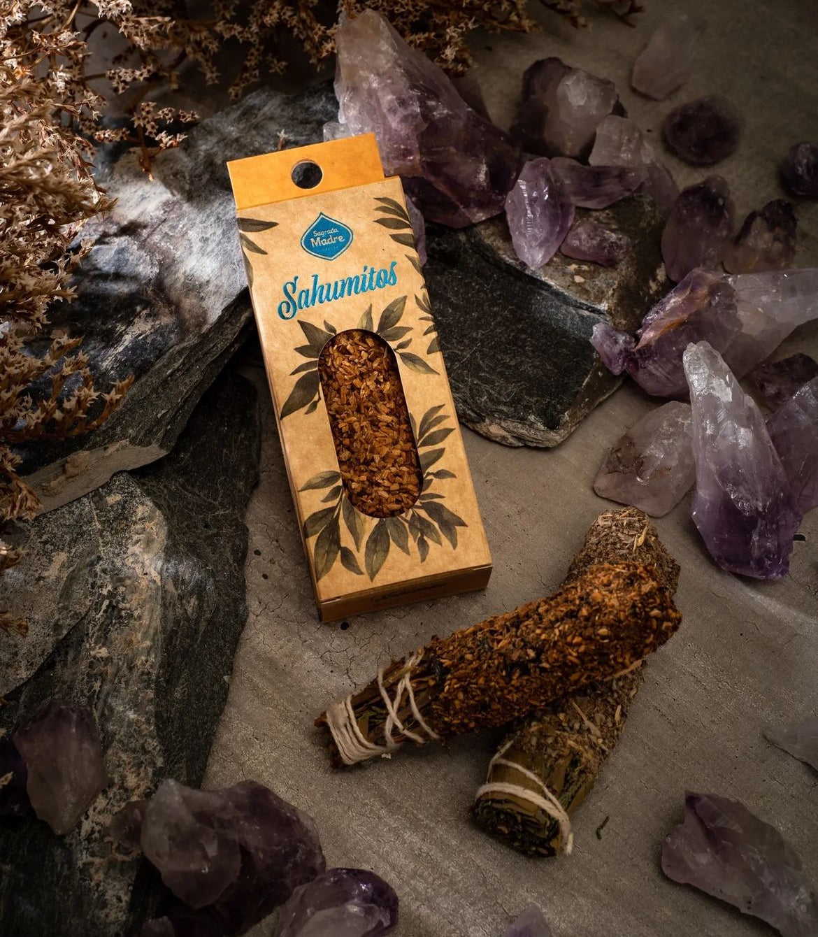 Boxed smudge stick lying among amethyst points and loose palo santo wood