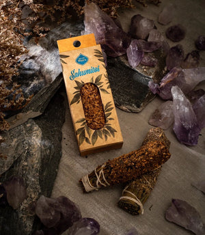 Boxed smudge stick lying among amethyst points and loose palo santo wood