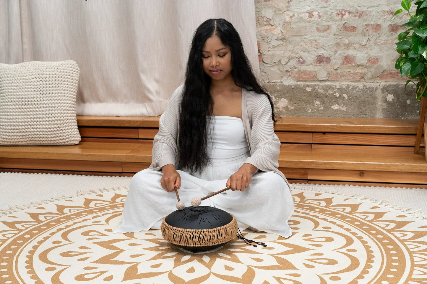 Black 10-inch steel tongue drum shown in a warm, softly lit styled scene.