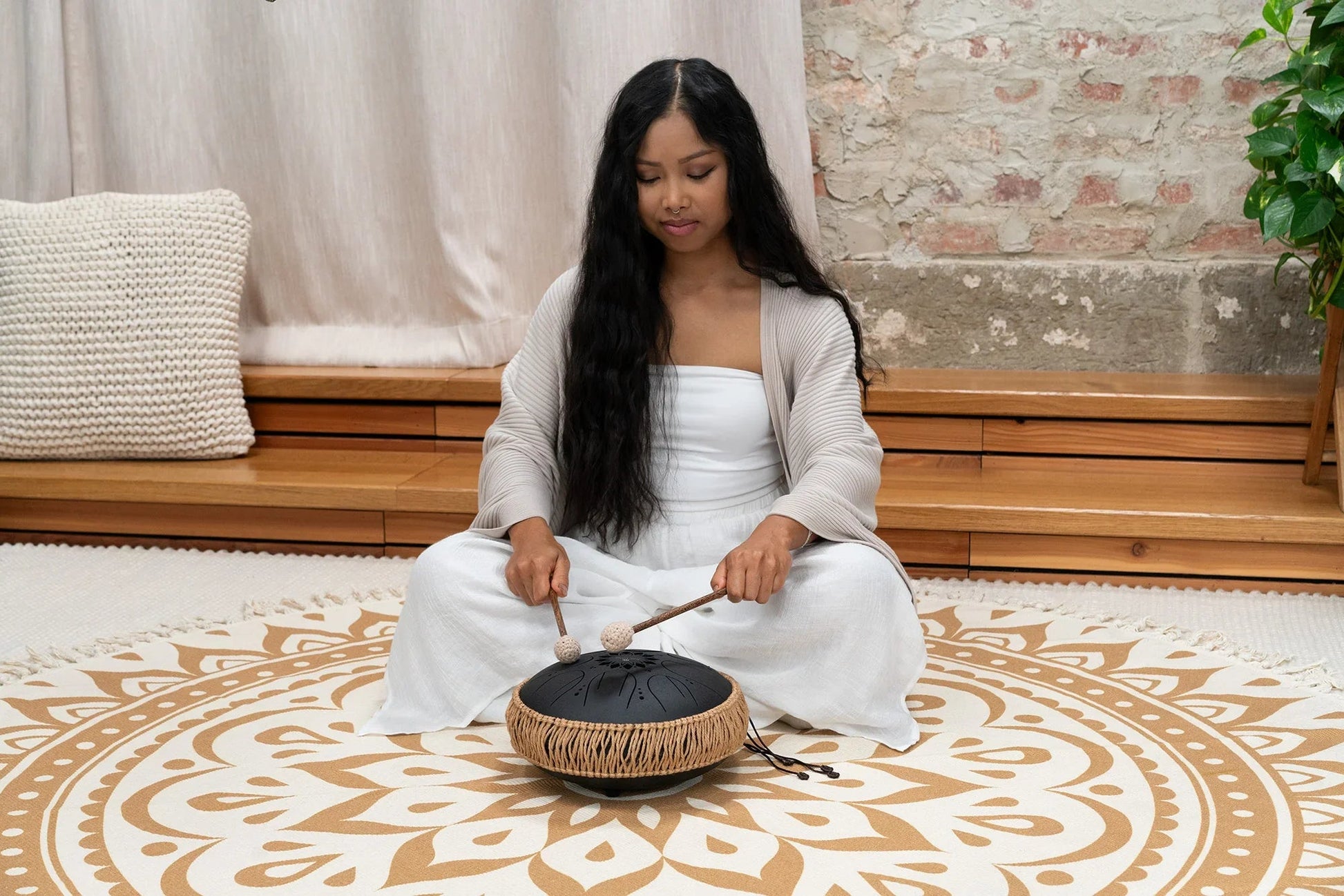Black 10-inch steel tongue drum shown in a warm, softly lit styled scene.
