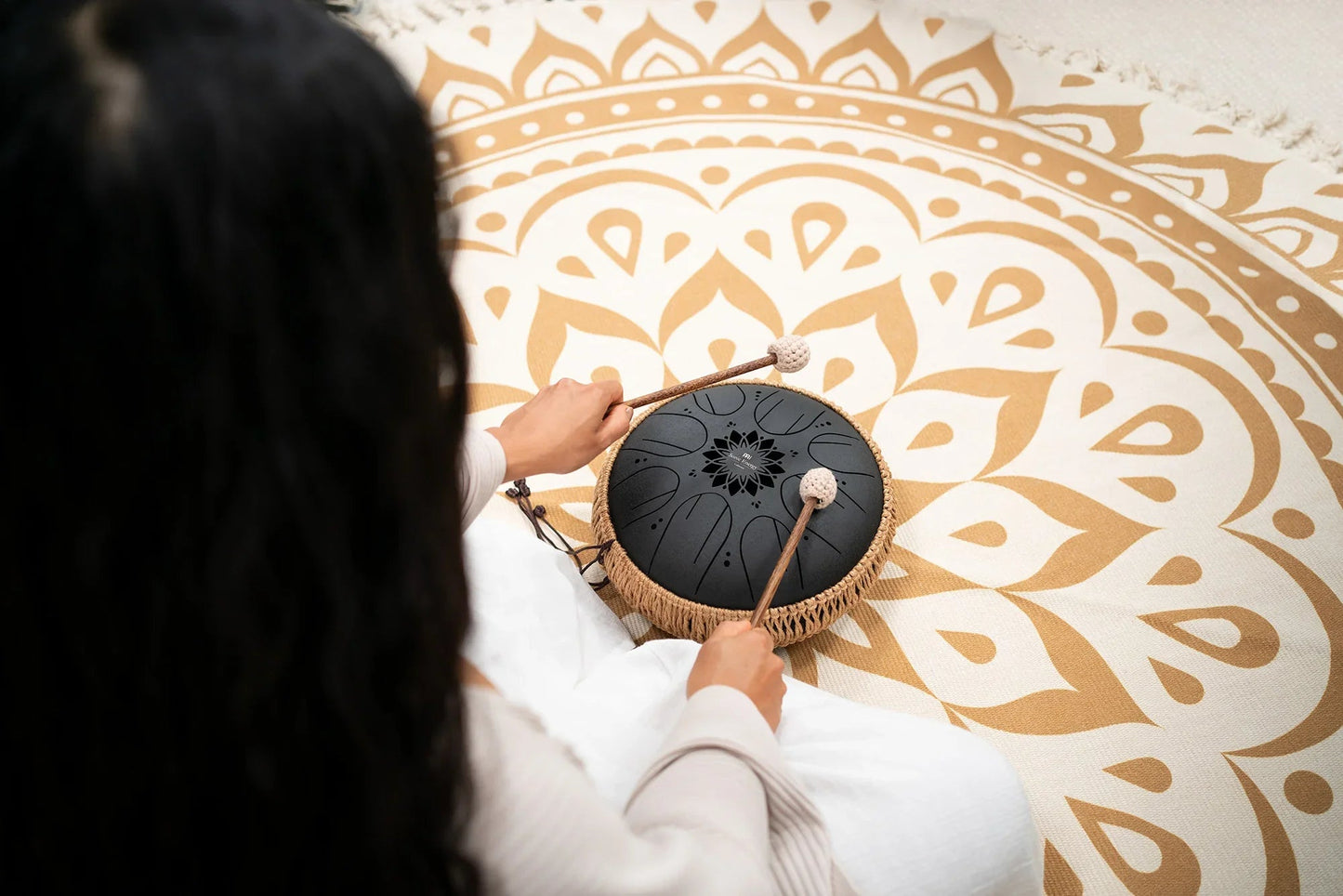 Black 10-inch steel tongue drum displayed in a calm, styled interior setting.