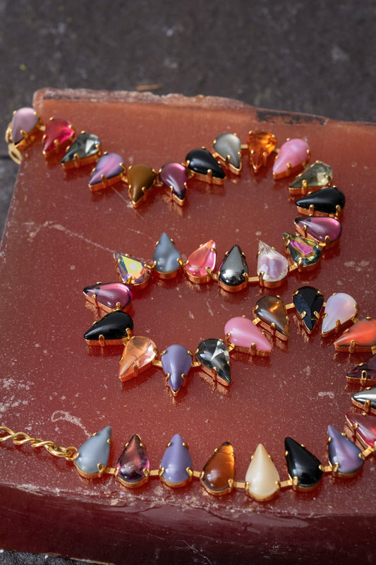 A gold-finish choker set with fang-shaped multicolored vintage glass stones.