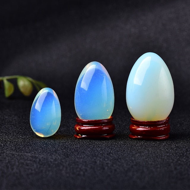 Polished carved crystal egg in assorted gemstones on a dark surface — view 1 of 10