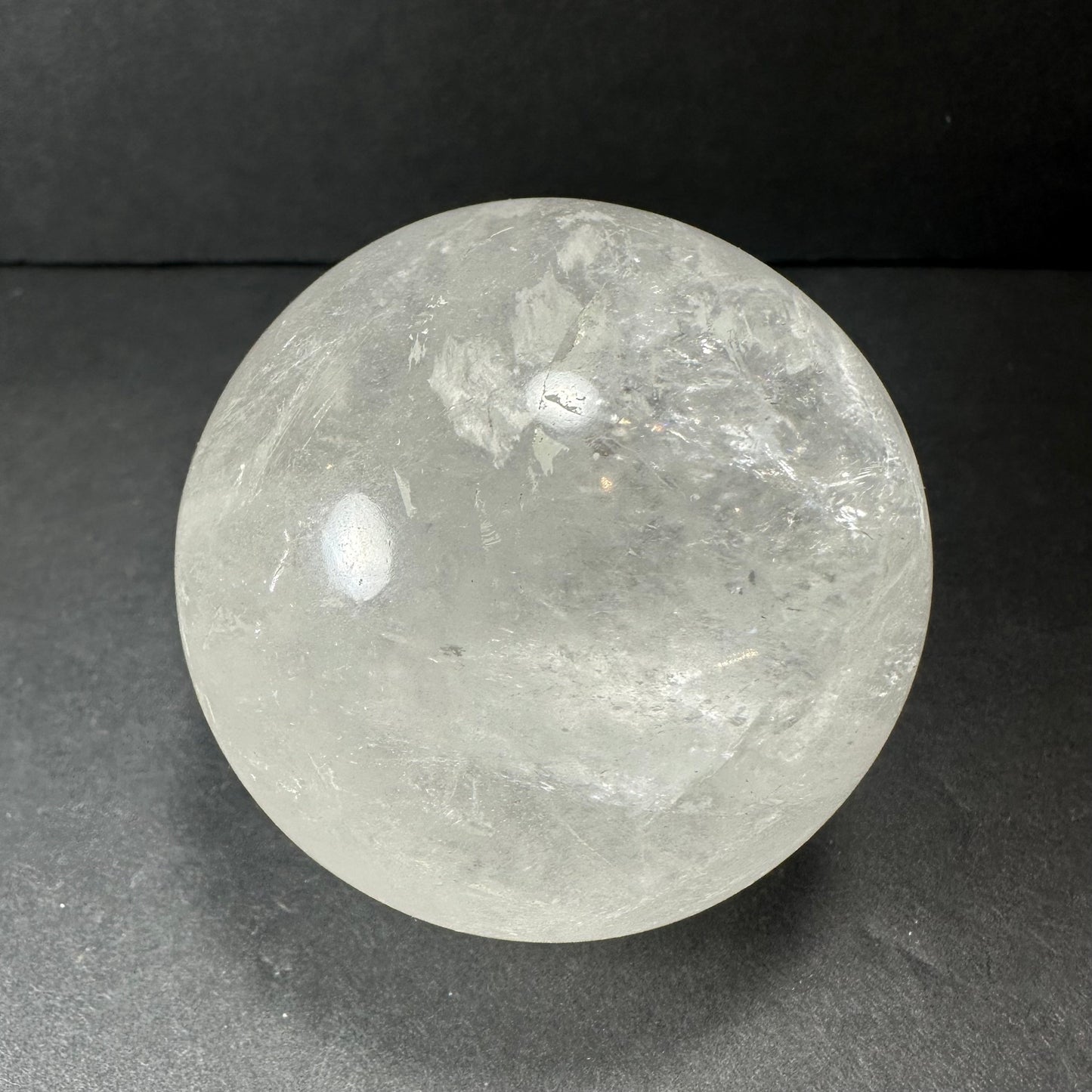 Clear quartz sphere showing internal veils and inclusions