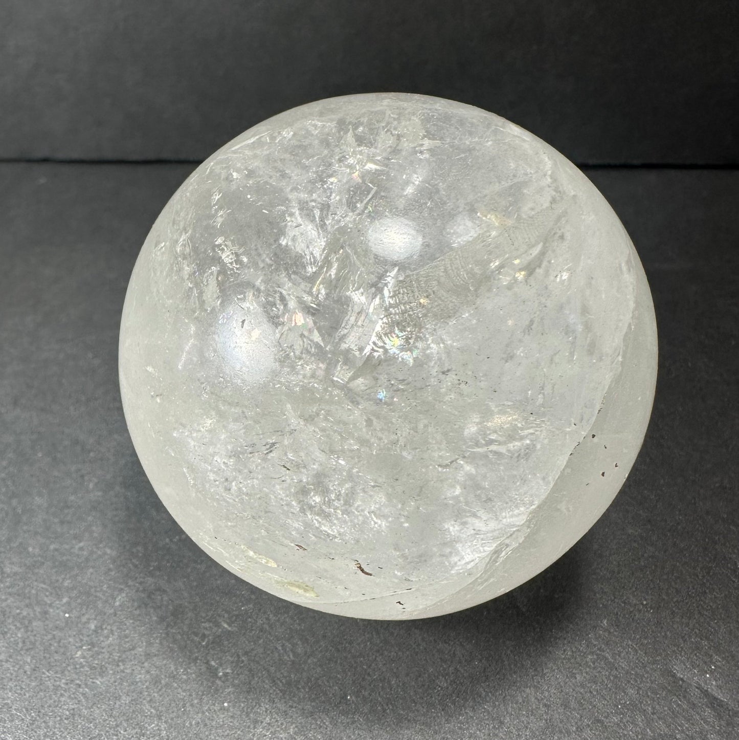 Polished clear quartz sphere on a dark surface