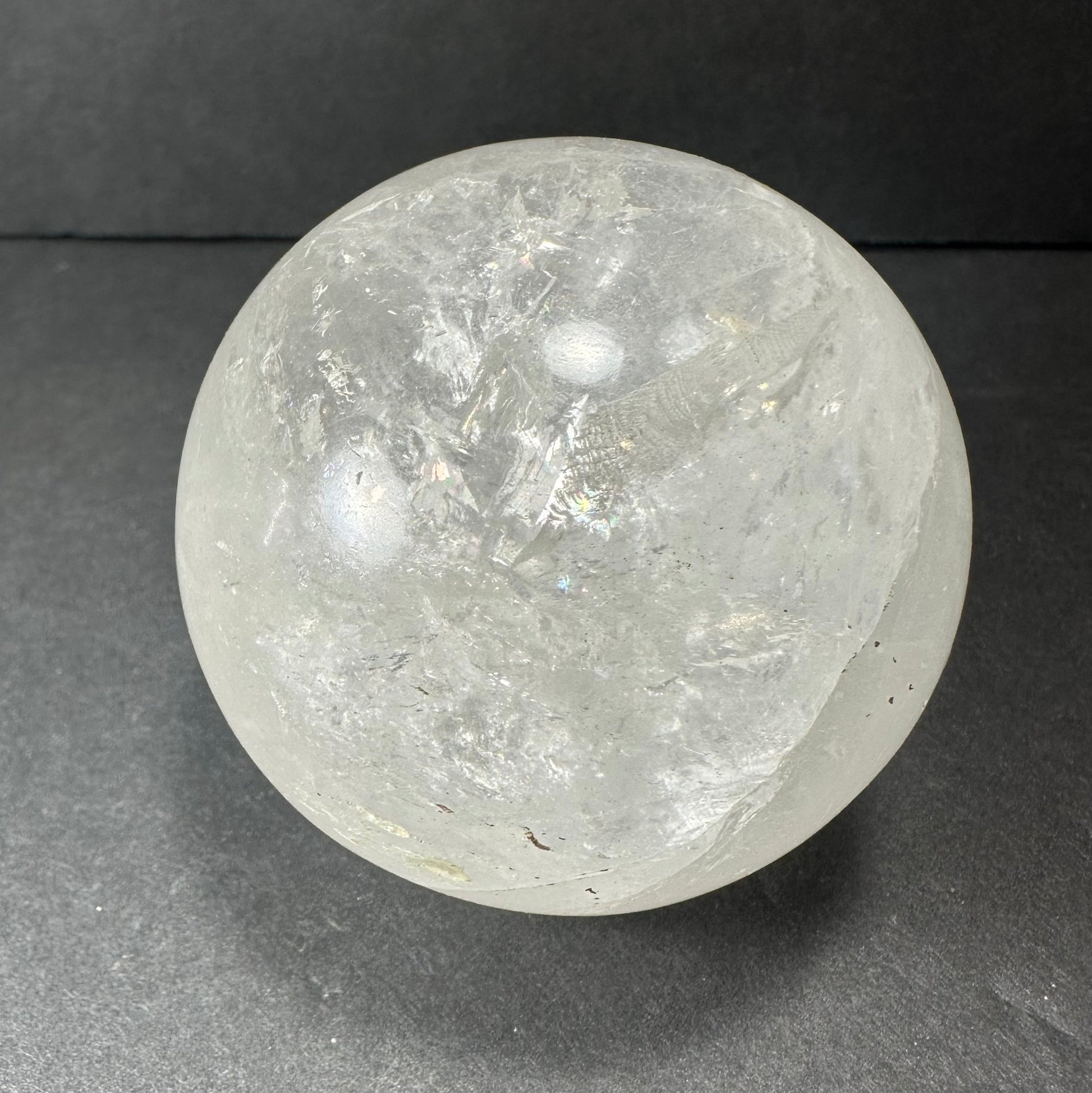 Polished clear quartz sphere on a dark surface