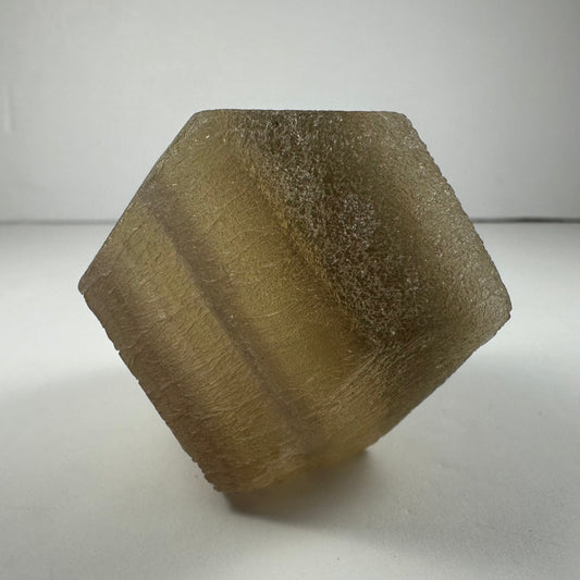 Polished fluorite dodecahedron with twelve pentagonal faces in banded green and purple, held in daylight