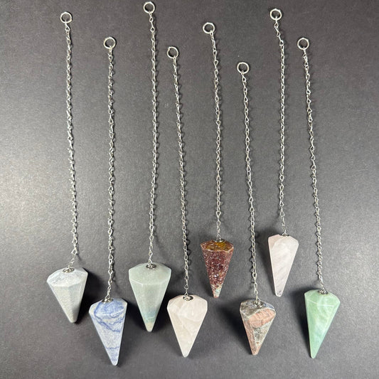 Faceted stone pendulum hanging from a seven-inch metal chain against a dark background