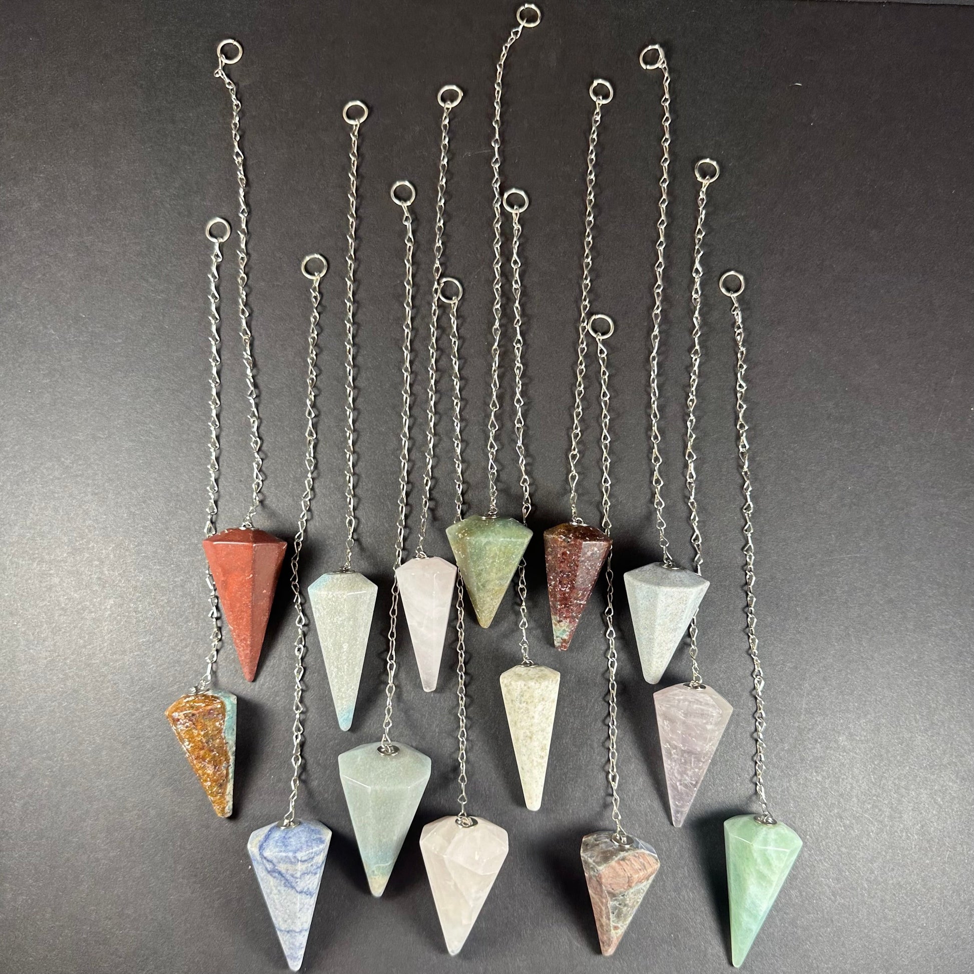 Faceted stone pendulum hanging from a seven-inch metal chain against a dark background — view 2
