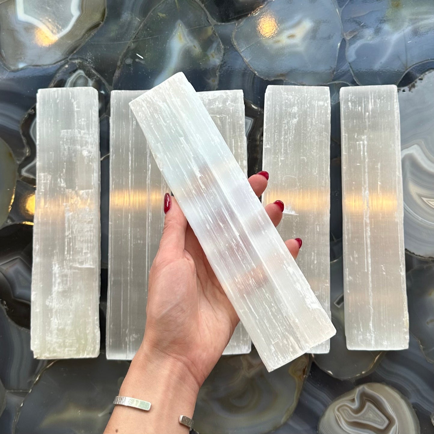 Rough selenite bar photographed lengthways against a dark background