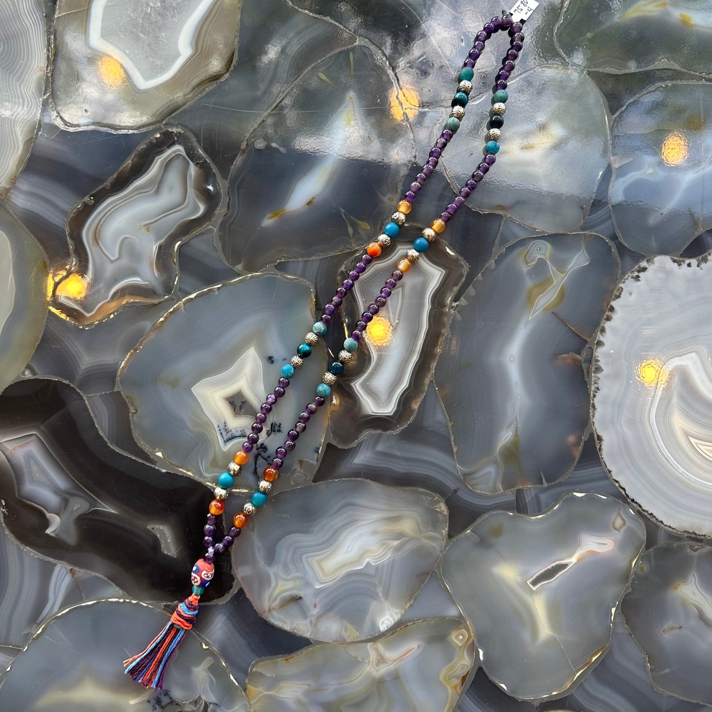 Amethyst mala necklace laid in a circle showing the mixed gemstone beads