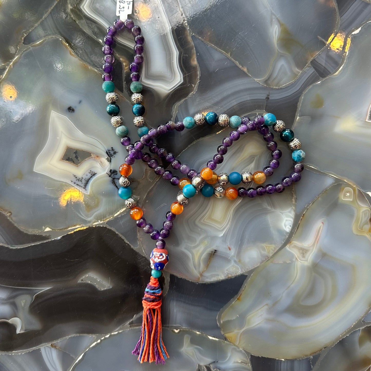 Amethyst mala necklace photographed against a dark background