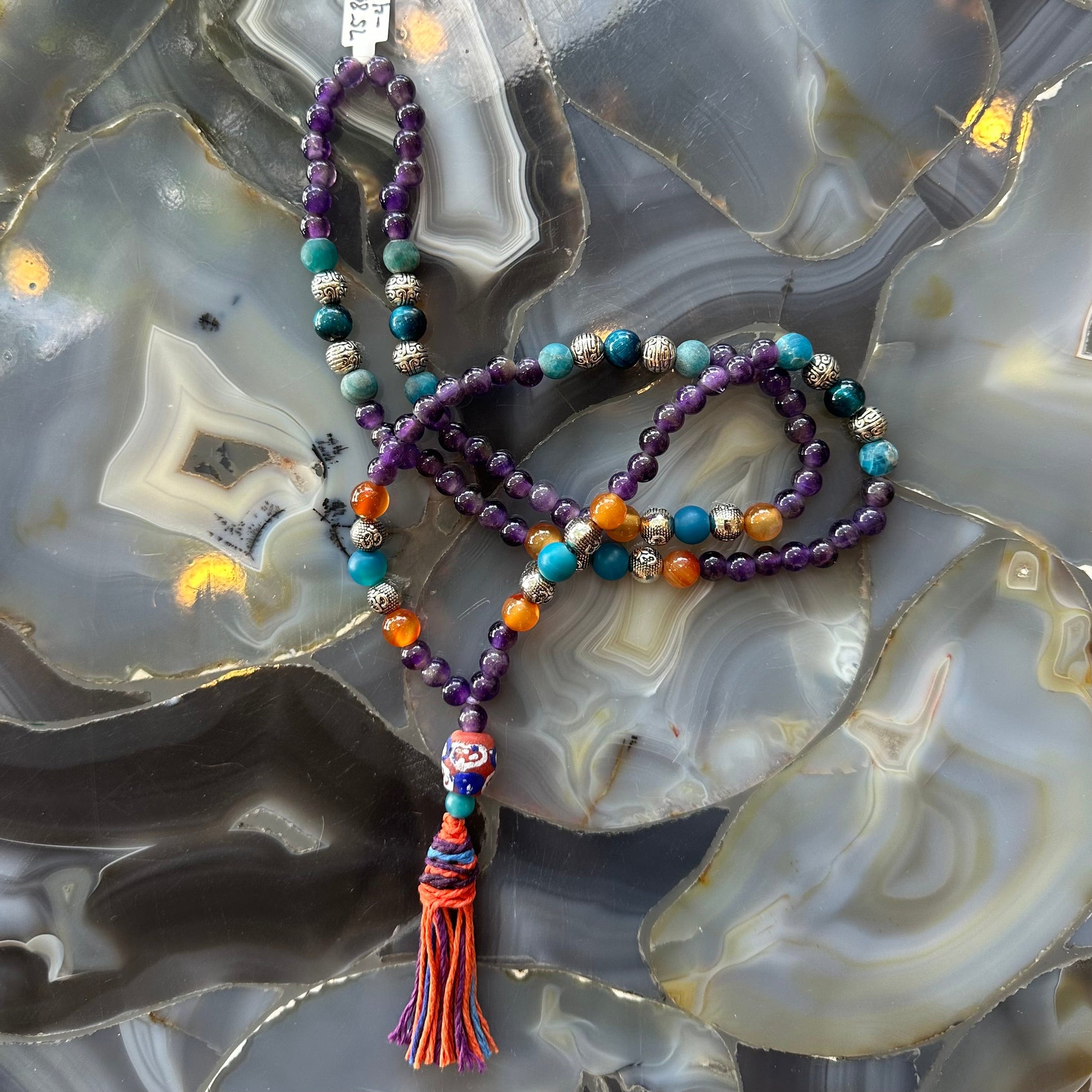 Amethyst mala necklace photographed against a dark background