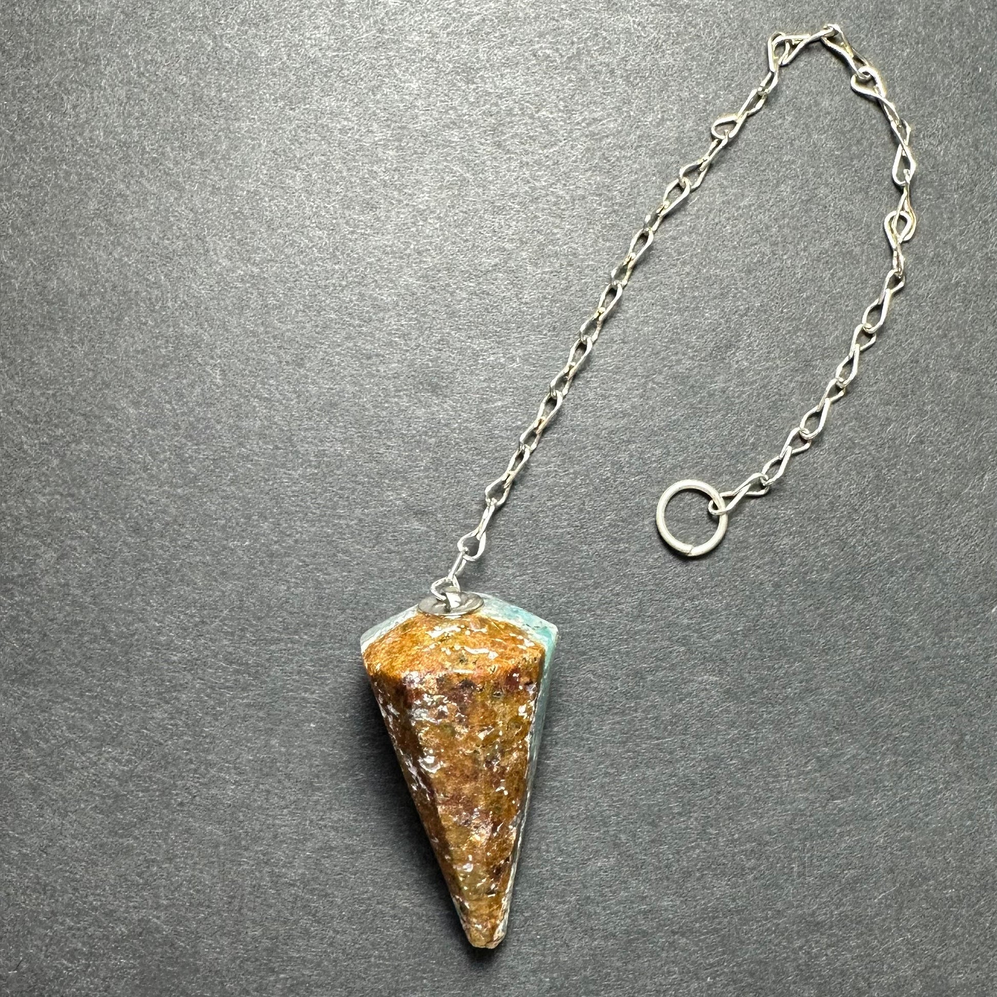 Faceted stone pendulum hanging from a seven-inch metal chain against a dark background — view 9