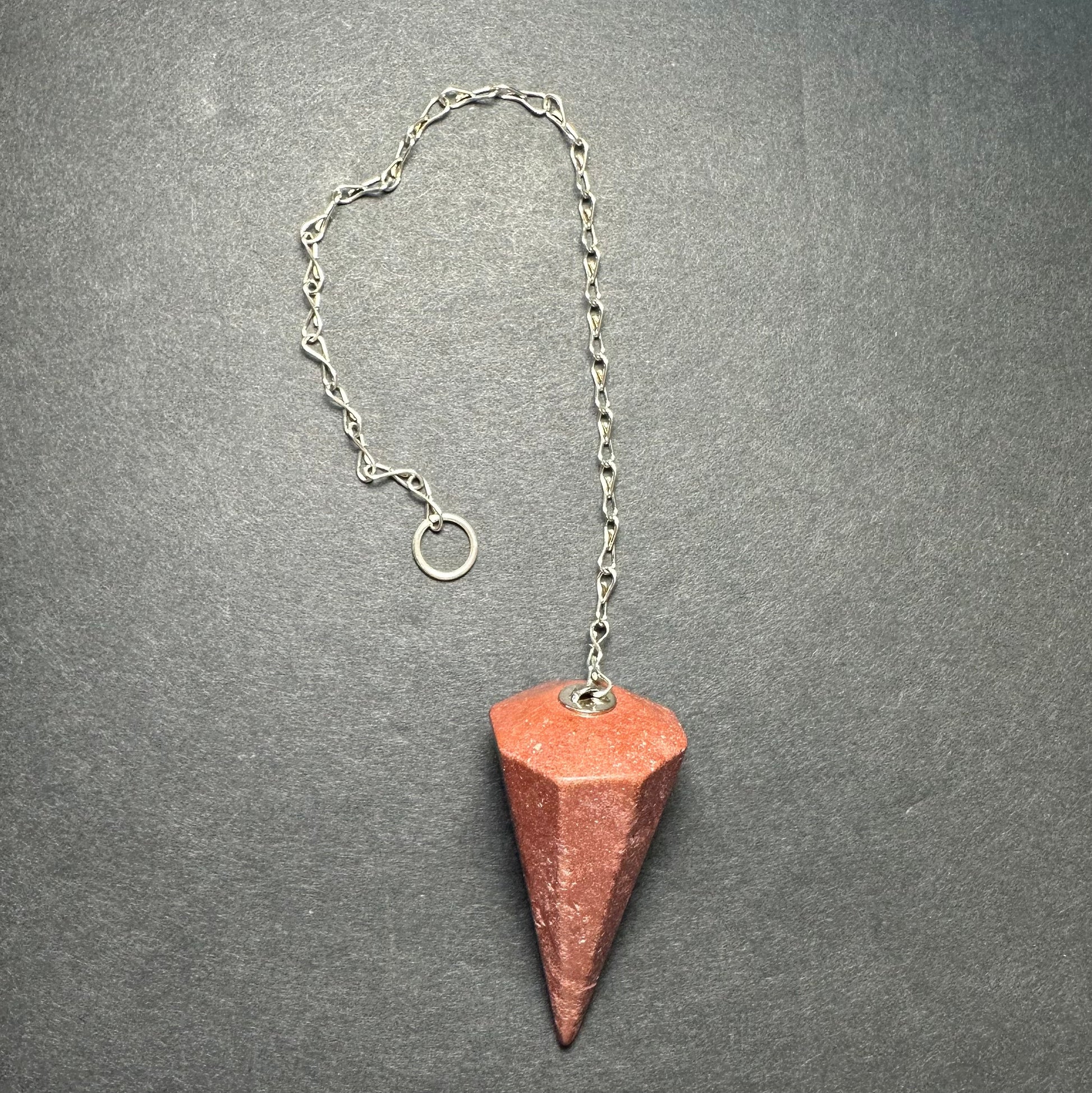 Faceted stone pendulum hanging from a seven-inch metal chain against a dark background — view 10