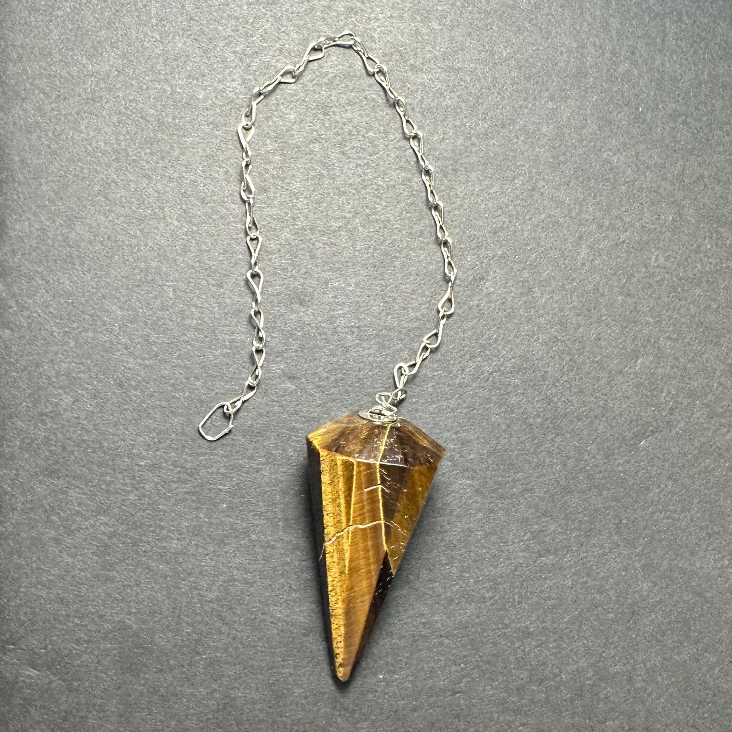 Faceted stone pendulum hanging from a seven-inch metal chain against a dark background — view 4