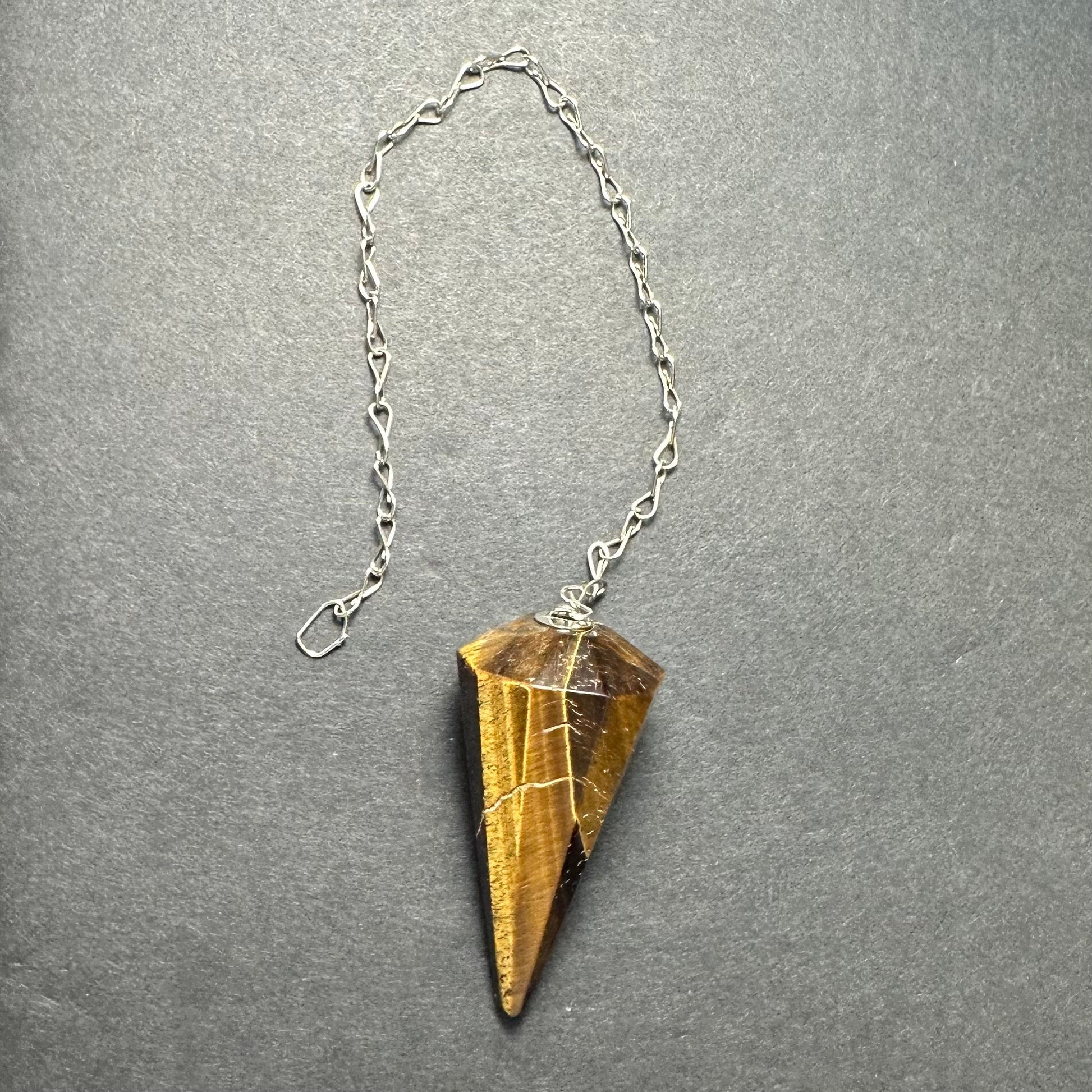 Faceted stone pendulum hanging from a seven-inch metal chain against a dark background — view 4
