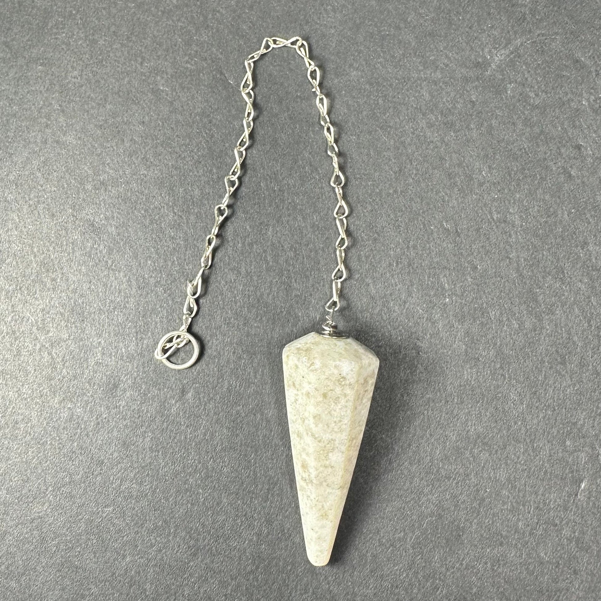 Faceted stone pendulum hanging from a seven-inch metal chain against a dark background — view 12