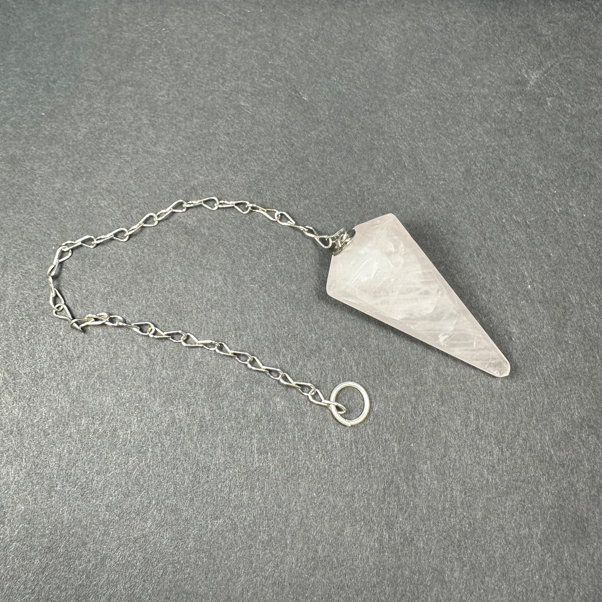 Faceted stone pendulum hanging from a seven-inch metal chain against a dark background — view 7