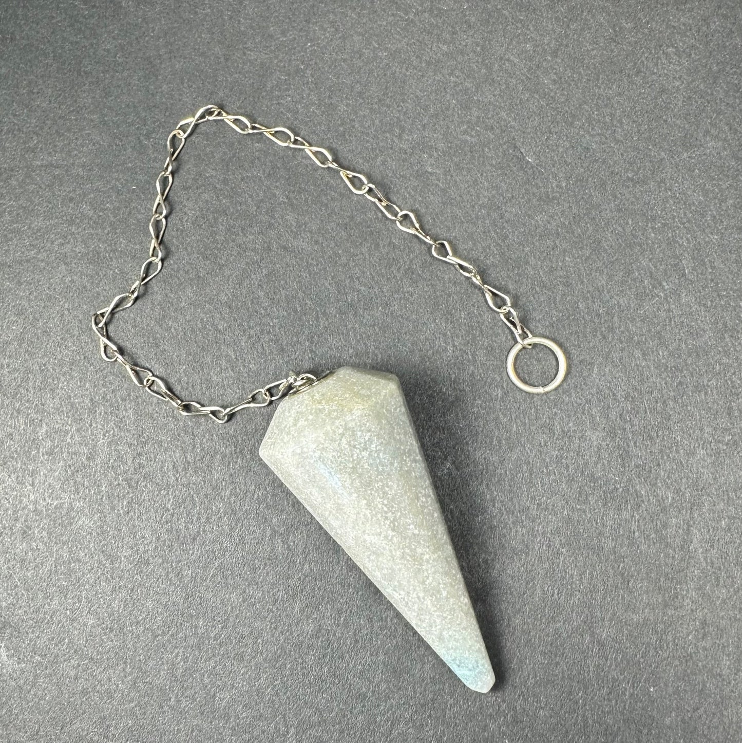 Faceted stone pendulum hanging from a seven-inch metal chain against a dark background — view 8