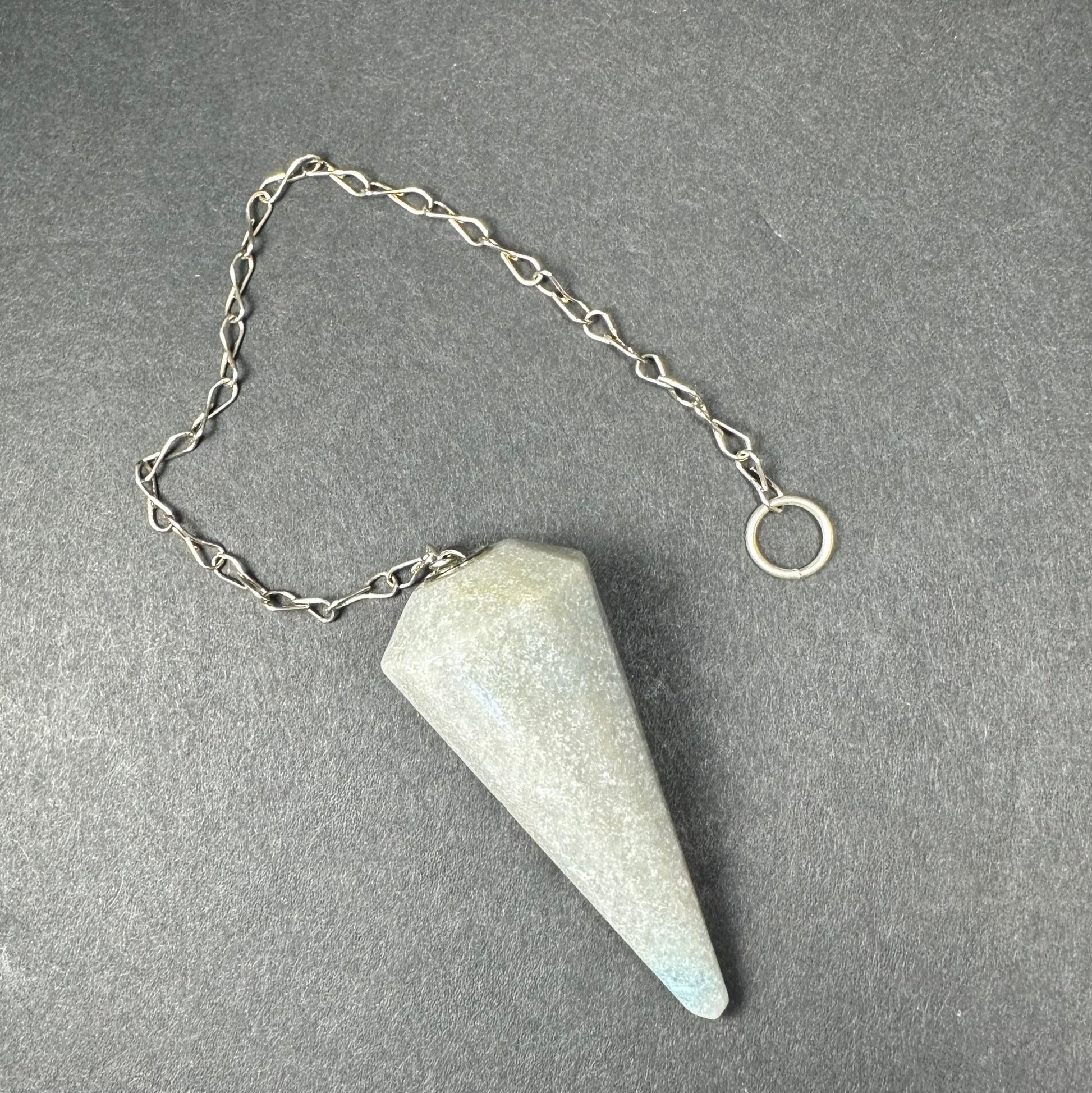 Faceted stone pendulum hanging from a seven-inch metal chain against a dark background — view 8