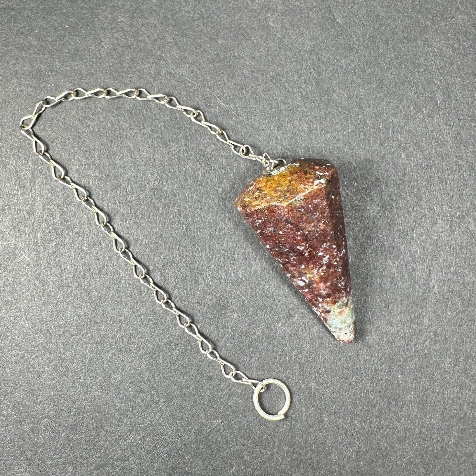 Faceted stone pendulum hanging from a seven-inch metal chain against a dark background — view 11