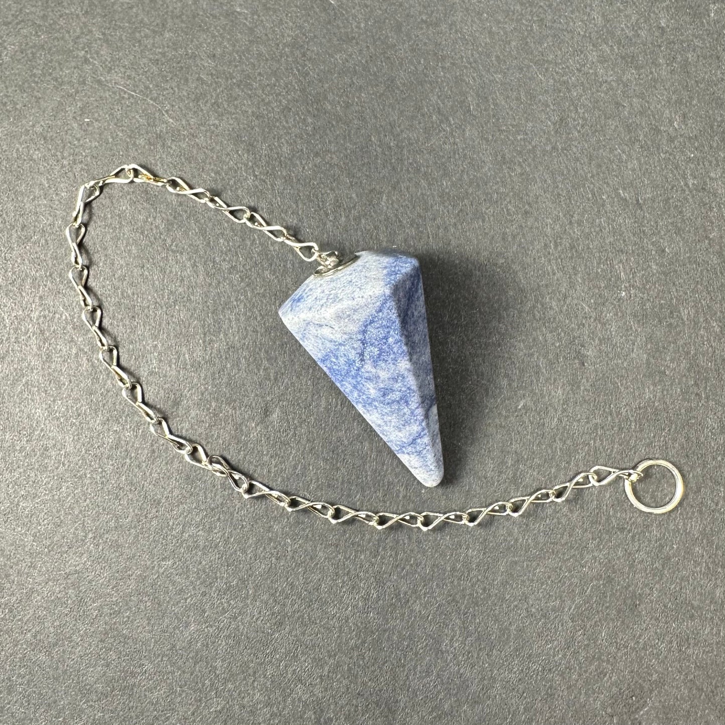 Faceted stone pendulum hanging from a seven-inch metal chain against a dark background — view 5