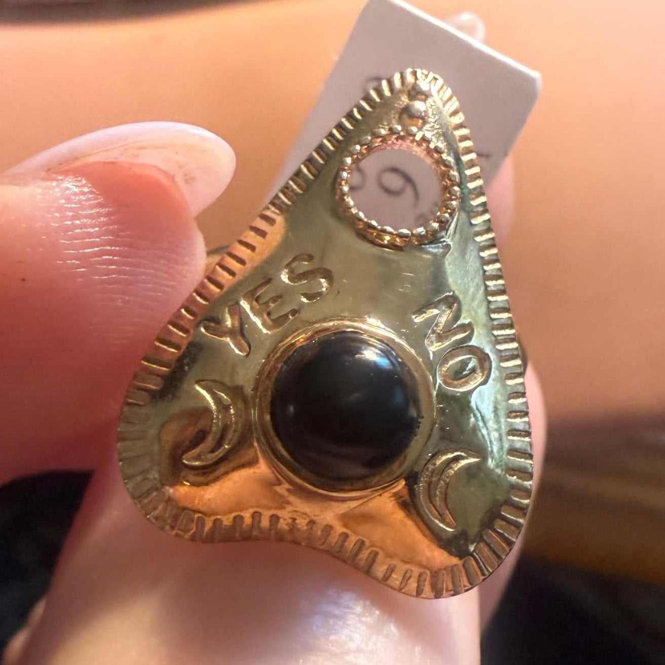 Planchette ring set with a black onyx cabochon, shown on the finger