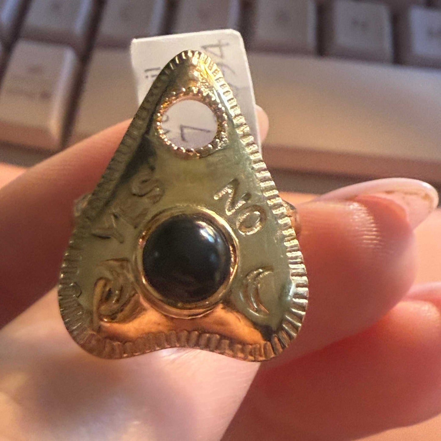 Planchette ring with a black onyx stone, viewed from the side on a hand