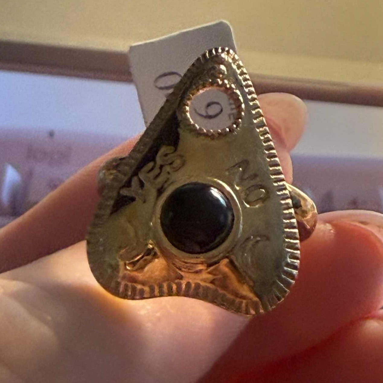 Planchette ring set with a polished black onyx cabochon, shown close up