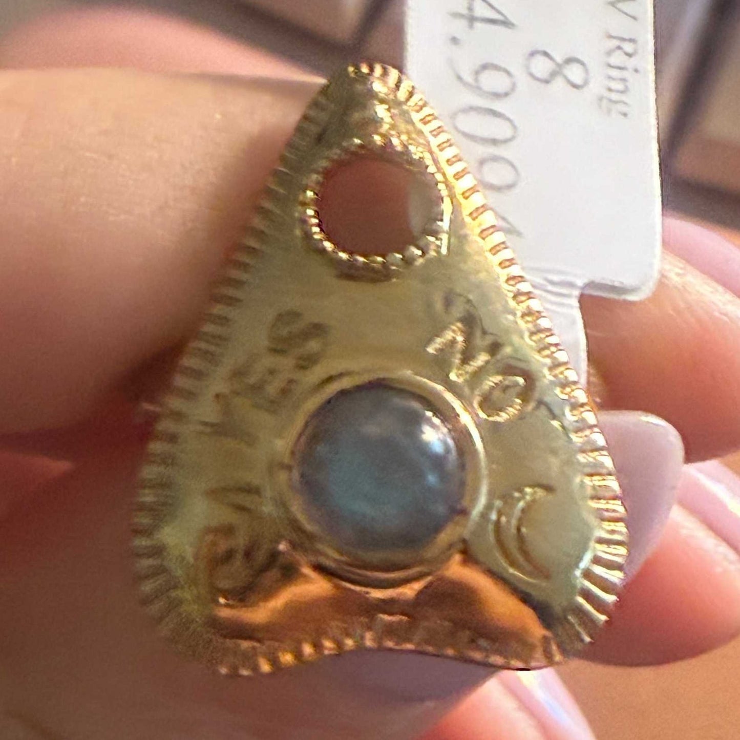 Planchette ring set with a blue-flashing labradorite cabochon, held to the light