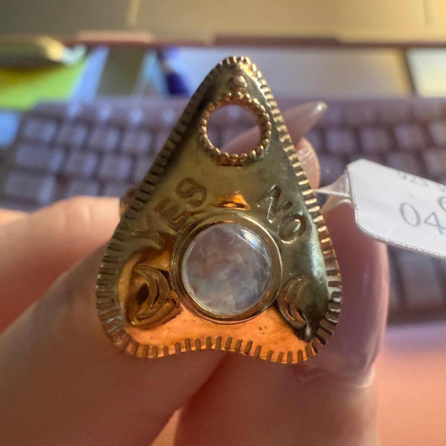 Planchette ring set with a pale rainbow moonstone, showing the engraved YES and NO lettering
