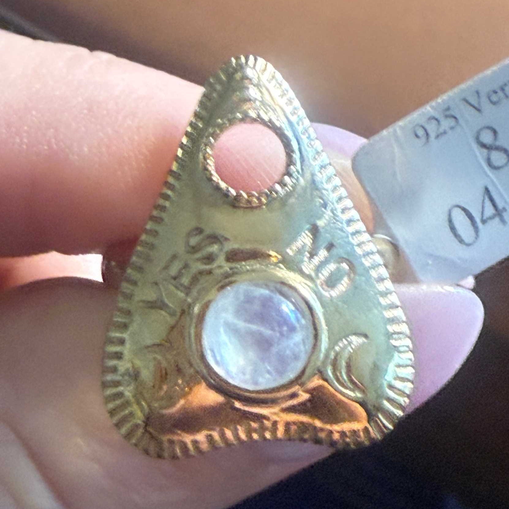 Planchette ring with a rainbow moonstone showing its blue sheen, worn on the finger