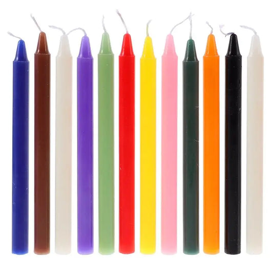Set of twelve colored ritual taper candles in red, pink, purple, blue, green, yellow, white and black, laid out in a row