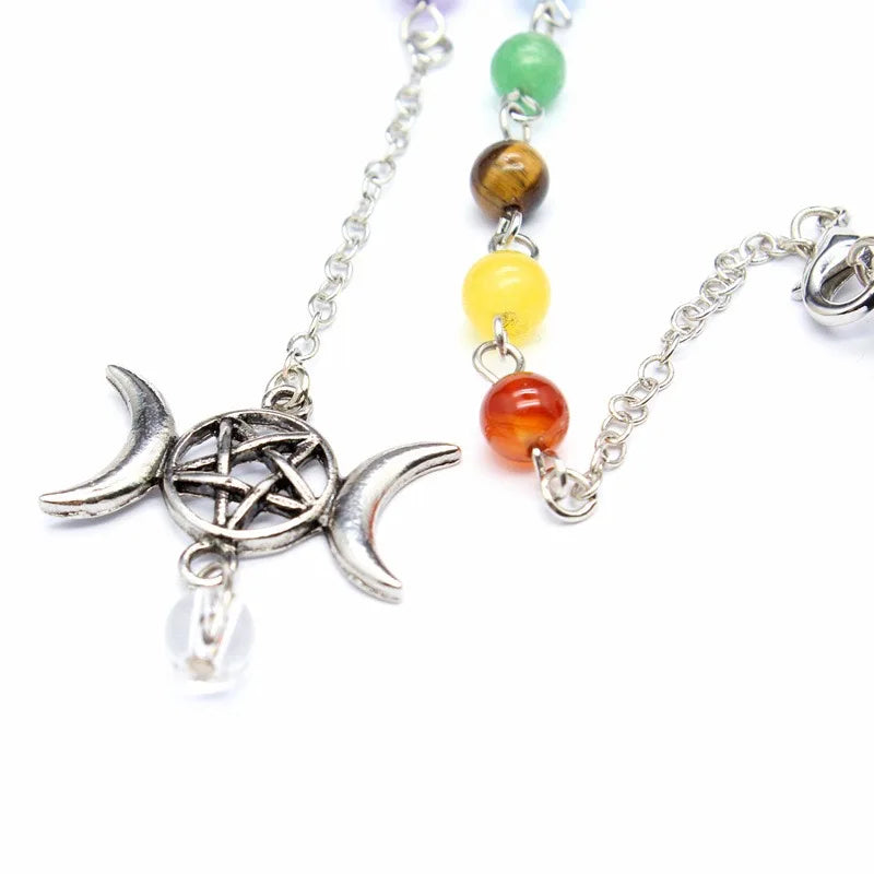 Hexagonal crystal point pendulum with a triple moon pentacle chakra cap, hanging from a fine silver-tone chain — product photo 3